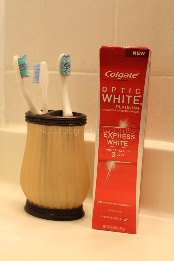 colgate optic white express white toothpaste in the box next to tooth brush holder in bathroom
